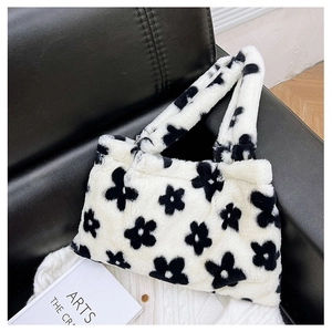 Dettaglio della borsa tote in peluche con motivo a fiori bianchi e neri su divano