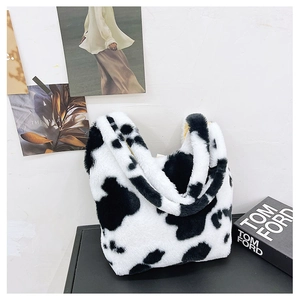 Close-up of fluffy black and white cow print plush handbag with soft yellow lining