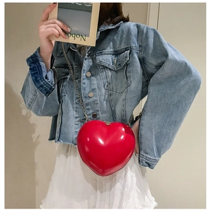 Chic red heart-shaped hard shell crossbody bag with metallic gold chain strap on model