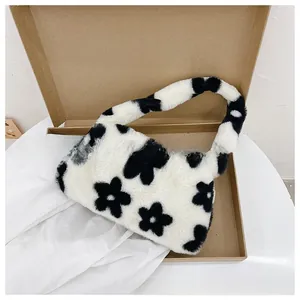 Detalle de bolso de hombro de felpa con patrones florales negros en una caja de cartón