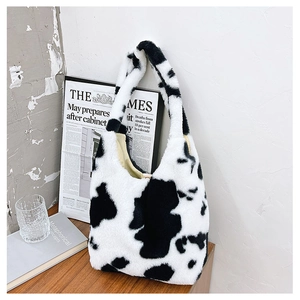 Close-up of soft fluffy cow print faux fur tote bag on a rustic wooden table background