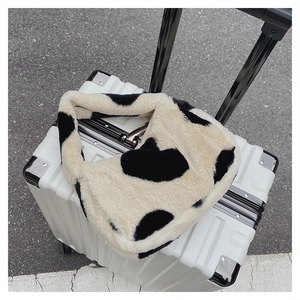 Détail d'un sac à bandoulière en fausse fourrure à motif vache sur une valise