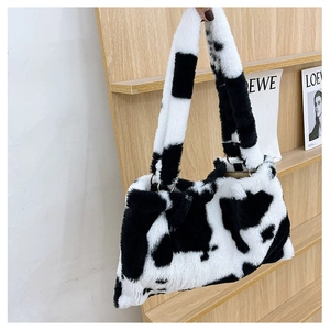 Dettaglio della borsa tote in peluche con stampa mucca bianca e nera e manici in metallo