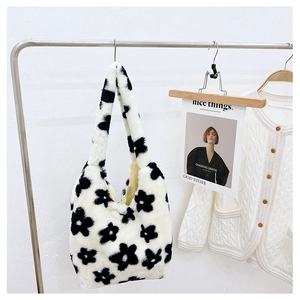 Close-up of soft plush floral tote bag with black flower patterns hanging on a metal rack
