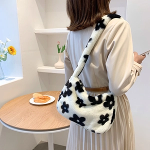 Sac sous le bras en fausse fourrure à fleurs noires sur blanc porté à l'épaule du mannequin
