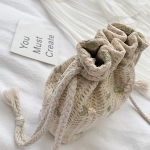 Sac seau tissé beige avec broderie florale rose sur fond de tissu blanc