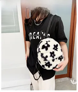 Détail d'un sac à dos en peluche à motif floral noir et blanc porté par un mannequin