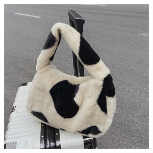 Détail du sac à main en peluche à motif vache avec fermeture éclair blanche
