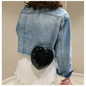 Detailed view of chic black heart-shaped mini chain bag worn as a crossbody purse