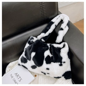 Dettaglio della borsa a mano in peluche con stampa mucca su sfondo in pelle con texture morbida