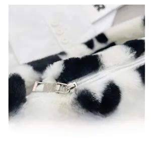 Detalle del bolso de hombro de pelo sintético con estampado de vaca y cremallera plateada