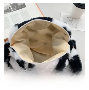 Draufsicht der flauschigen Tasche mit Kuhmuster zeigt Innenraum und goldenen Reißverschluss