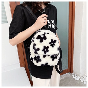 Gros plan d'un sac à dos en peluche à fleurs noires et blanches avec bretelles réglables