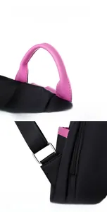 Detail of pink ergonomic handle and reinforced triangular stress points on black backpack