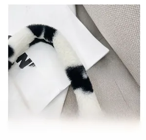 Detalle del asa ajustable en un bolso de hombro de felpa suave con un estampado de vaca