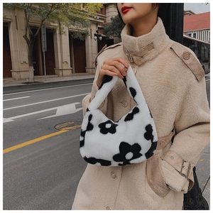 Détail du sac à main en peluche à fleurs noir et blanc porté avec un manteau d'hiver