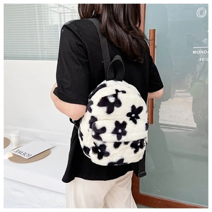 Gros plan d'un sac à dos en peluche à fleurs noir et blanc porté par un mannequin