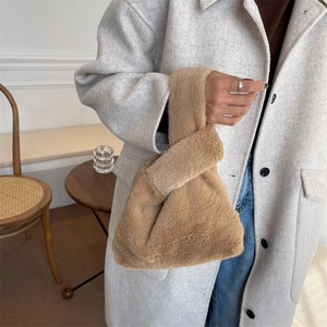Sac cabas en fausse fourrure camel avec poignée nouée porté par un mannequin en manteau