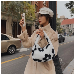 Détail du sac à main en peluche à motif floral noir et blanc avec une veste en polaire