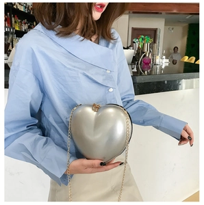 Detailed view of a silver heart-shaped hard shell clutch bag with gold chain strap