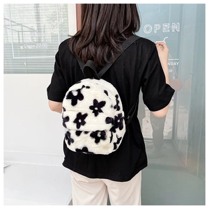 Gros plan d'un mini sac à dos en peluche blanche avec motifs floraux noirs porté