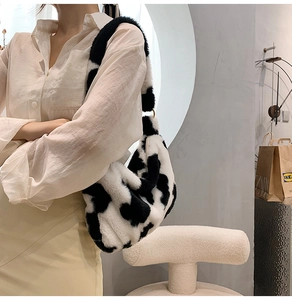 Schicke Plüsch-Schultertasche mit Kuhmuster, getragen von einem Modell im Innenraum