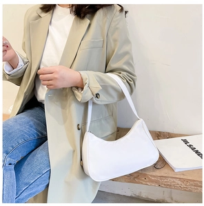 Close-up of minimalist white crescent underarm bag worn by model in casual style
