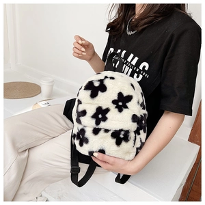Gros plan sur un sac à dos en peluche à fleurs noir et blanc porté par un mannequin