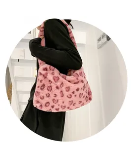 Détail d'un sac bandoulière en peluche rose à motifs de cœurs porté par un mannequin
