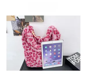 Pink leopard print faux fur tote bag next to a tablet and fashion magazine on a desk