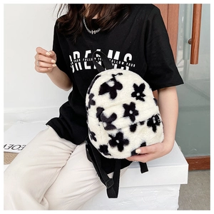 Détail du sac à dos en peluche douce avec des motifs floraux noirs sur fond blanc pur