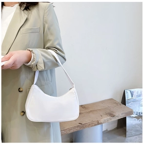 White nylon hobo bag shown on a model, featuring a modern minimalist crescent shape