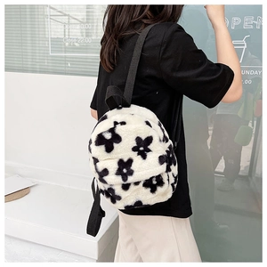 Gros plan d'un mini sac à dos en peluche blanche avec motifs fleurs noires sur le dos