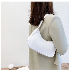 Detailed back view of a woman wearing a minimalist white crescent hobo shoulder bag