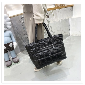 Dettaglio della borsa tote trapuntata nera in nylon lucido con tasca esterna a zip