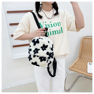 Gros plan du sac à dos en peluche blanche avec motif fleurs noires et bretelles