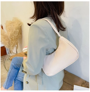 Detail of minimalist cream nylon shoulder bag styled with green blazer in a cafe setting