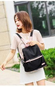 Detail of waterproof nylon backpack with pink contrast zippers and side pocket on model