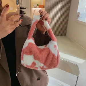 Sac à épaule en peluche à motif vache rose et blanc porté par un mannequin en intérieur