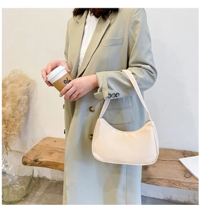 Minimalist beige nylon crescent shoulder bag shown in a stylish lifestyle setting