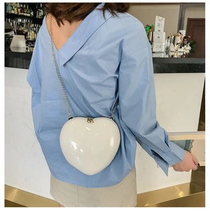 Detail view of the mini white heart shaped crossbody bag with elegant gold chain strap