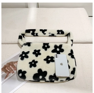 Détail du sac à main en peluche beige avec motif de fleurs noires et bandoulière