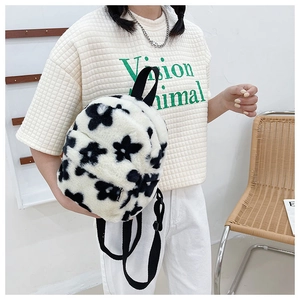 Vue détaillée de la texture en peluche blanche et des motifs floraux noirs sur le mini sac