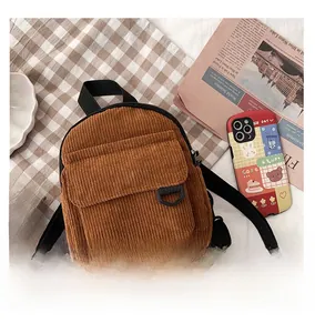 Detailansicht des braunen Cord-Rucksacks mit großer Klappentasche und modischen Accessoires