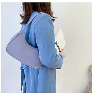 Close-up of a lilac nylon hobo bag styled on a model's shoulder with a blue blazer
