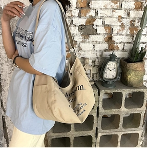 Dettaglio della tasca laterale della borsa tote in tela beige e tracolla larga