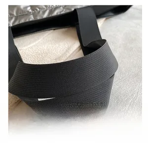 Close-up of metallic silver quilted fabric and durable black nylon shoulder strap