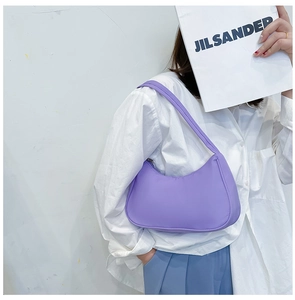 Detail view of the purple nylon crescent underarm bag worn on a model's shoulder