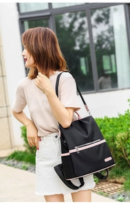 Fashionable black water-resistant nylon backpack with pink trim shown from a side view