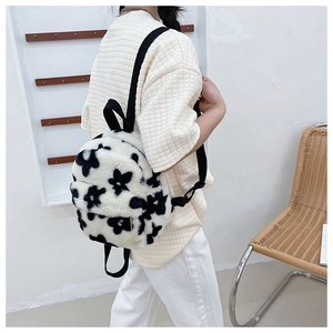 Gros plan d'un sac à dos en peluche à fleurs noir et blanc porté par un mannequin en studio